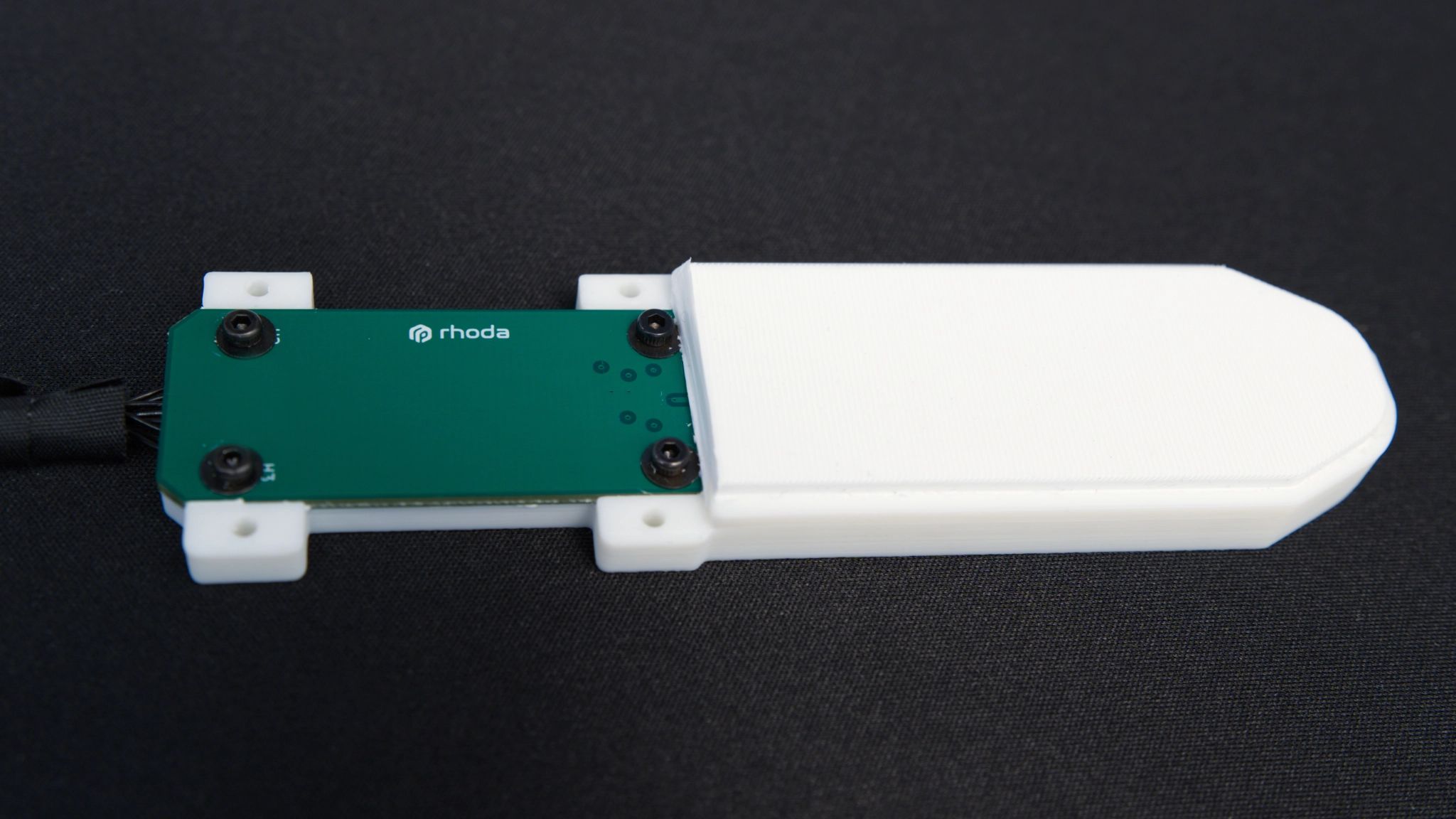 Rhoda tactile sensor with a white contact pad and green circuit board, packaged for a robotic gripper; annotated height of 8 mm from the tabletop to the top of the white silicone